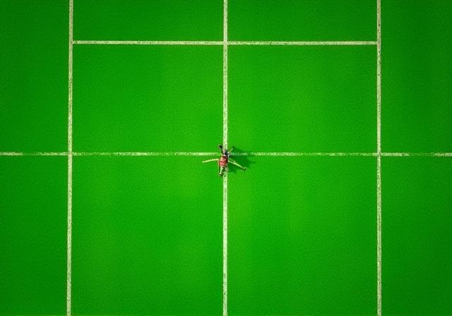 Grøn kunstgræsbane med hvide linjer set fra oven.